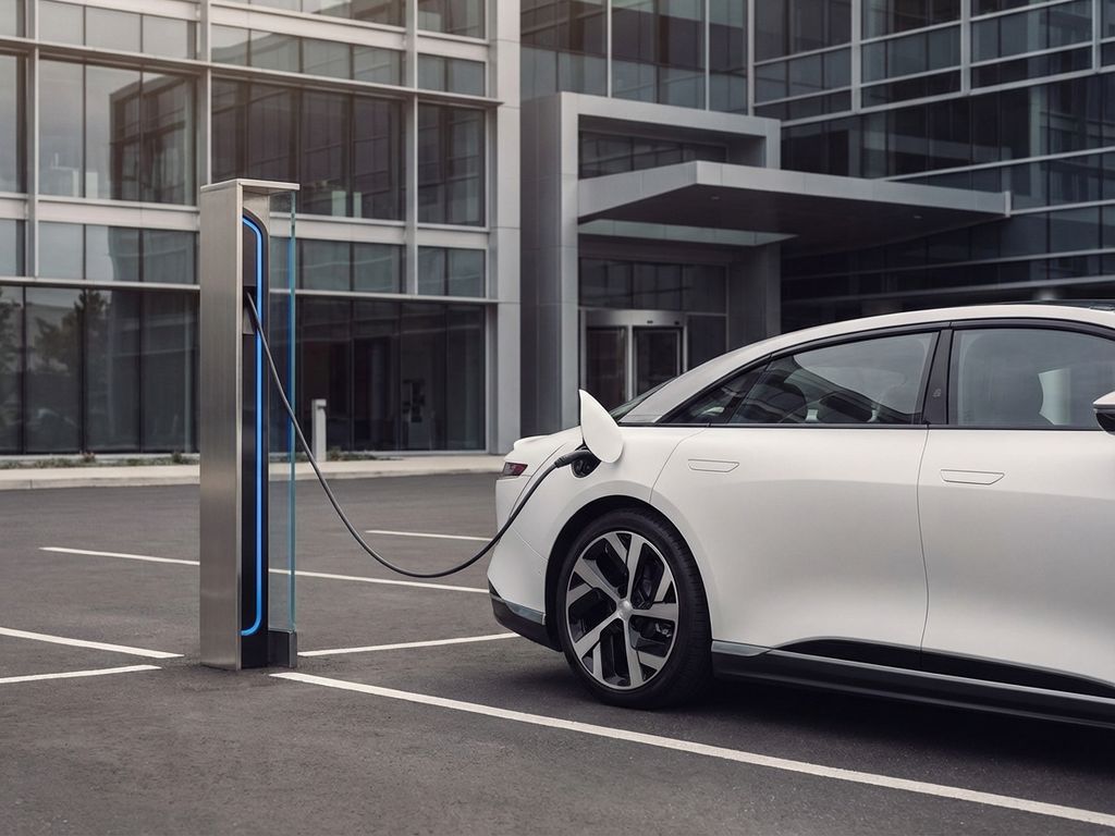 Elektrische auto laadt op bij moderne laadpaal in bedrijfsparkeerplaats met minimalistisch glazen gebouw op achtergrond