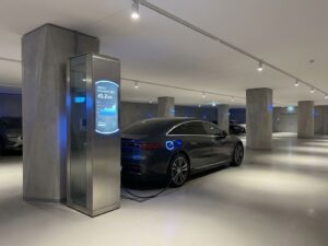 Elektrische auto laadt bij moderne laadpaal met digitaal display in minimalistische parkeergarage met betonnen pilaren