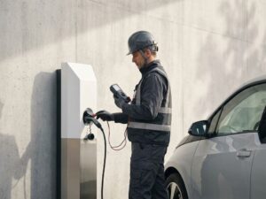 Professionele inspecteur test elektrisch voertuig laadstation met digitaal testapparaat in moderne witte ruimte