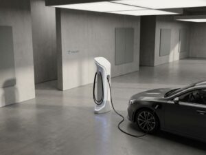 Moderne elektrische auto oplaadstation met witte oppervlakken en laadkabel aangesloten op voertuig in minimalistische ruimte