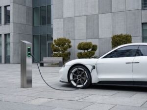 Witte elektrische auto laadt bij moderne laadpaal voor kantoorgebouw met strakke grijze architectuur