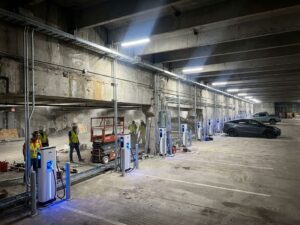 Moderne betonnen parkeergarage wordt omgebouwd tot EV-laadstation met witte laadpalen en blauwe LED-verlichting