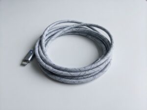 Elegante oplaadkabel met geometrische patronen op witte ondergrond, minimalistische productfotografie met blauwe accenten