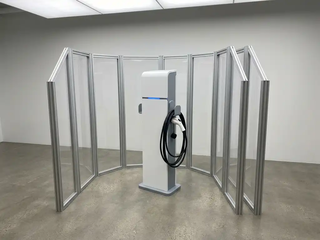 Witte EV-laadpaal beschermd door transparante polycarbonaat panelen op betonnen vloer tegen minimalistische muur