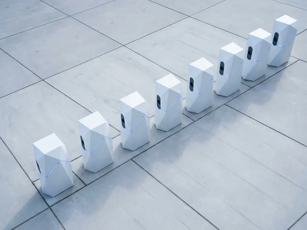 Rij witte elektrische laadstations in symmetrische opstelling op betonnen ondergrond in Nederlandse stedelijke omgeving