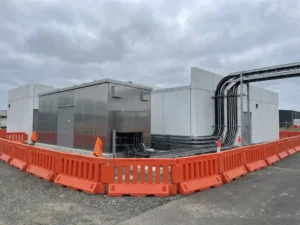 Elektrisch transformatorstation met oranje bouwhekken en moderne stroominfrastructuur onder bewolkte hemel
